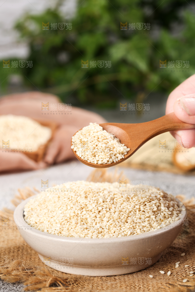 一碗脱皮白芝麻和勺子上挖着芝麻