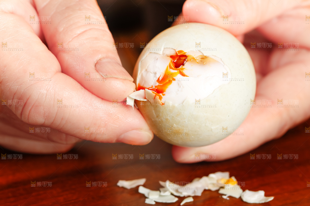木板上手拿流油的海鸭蛋