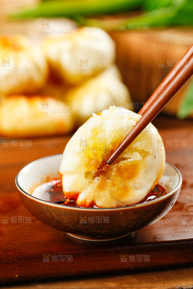 筷子夹着蘸辣椒的煎包