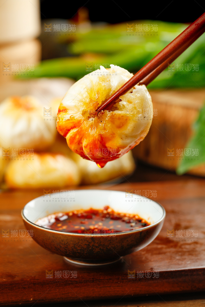 筷子夹着蘸辣椒的煎包