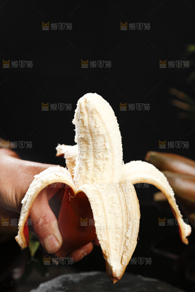 黑底上手拿着剥皮的红皮香蕉