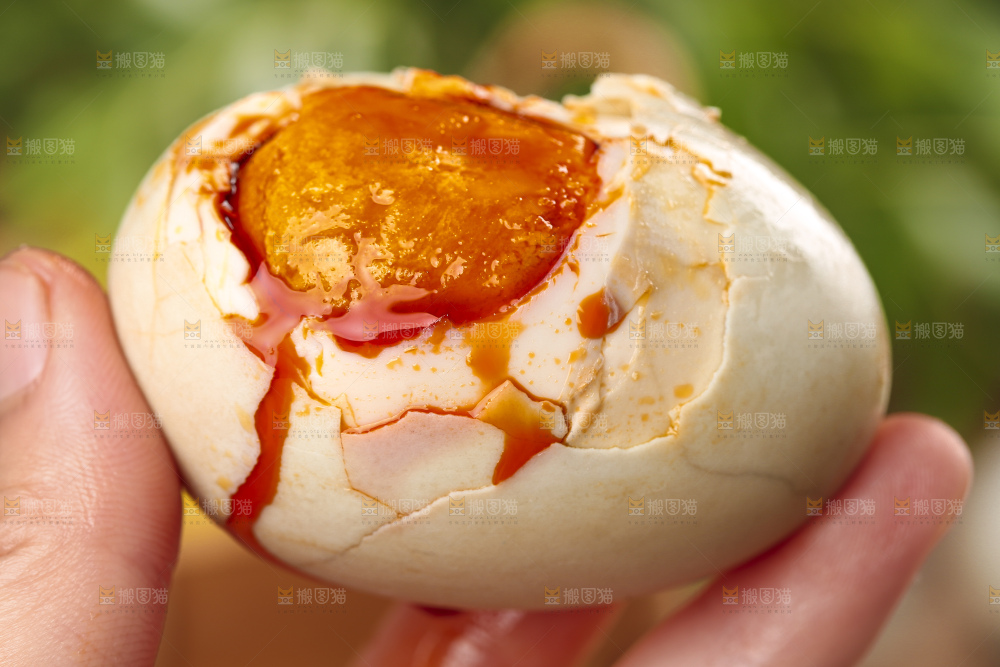 浅底上手拿一个流油的咸鸭蛋