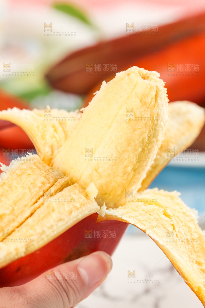 浅底上手拿剥皮的红皮香蕉