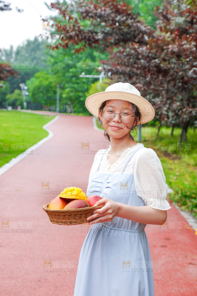 女孩手里端着一篮芒果