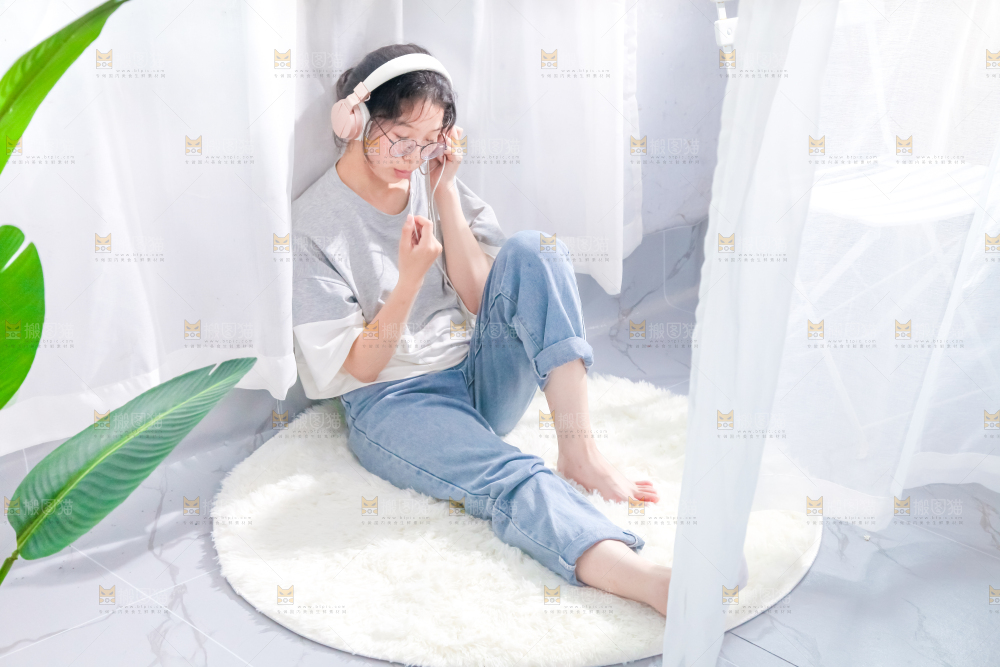 毛毯上坐着一位带耳机的女孩