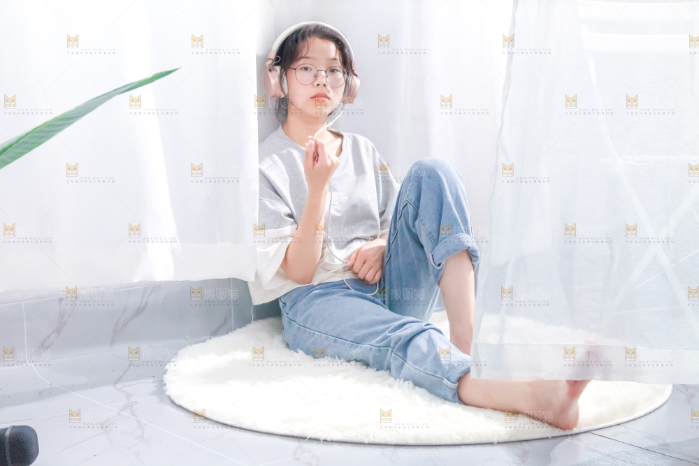 毛毯上坐着一位带耳机的女孩