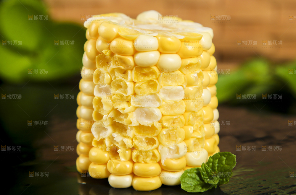 黑石板上放着掰开的甜玉米