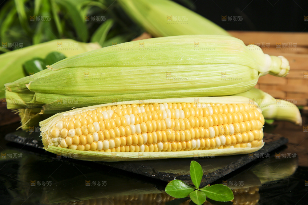 黑石板上放着剥皮的玉米