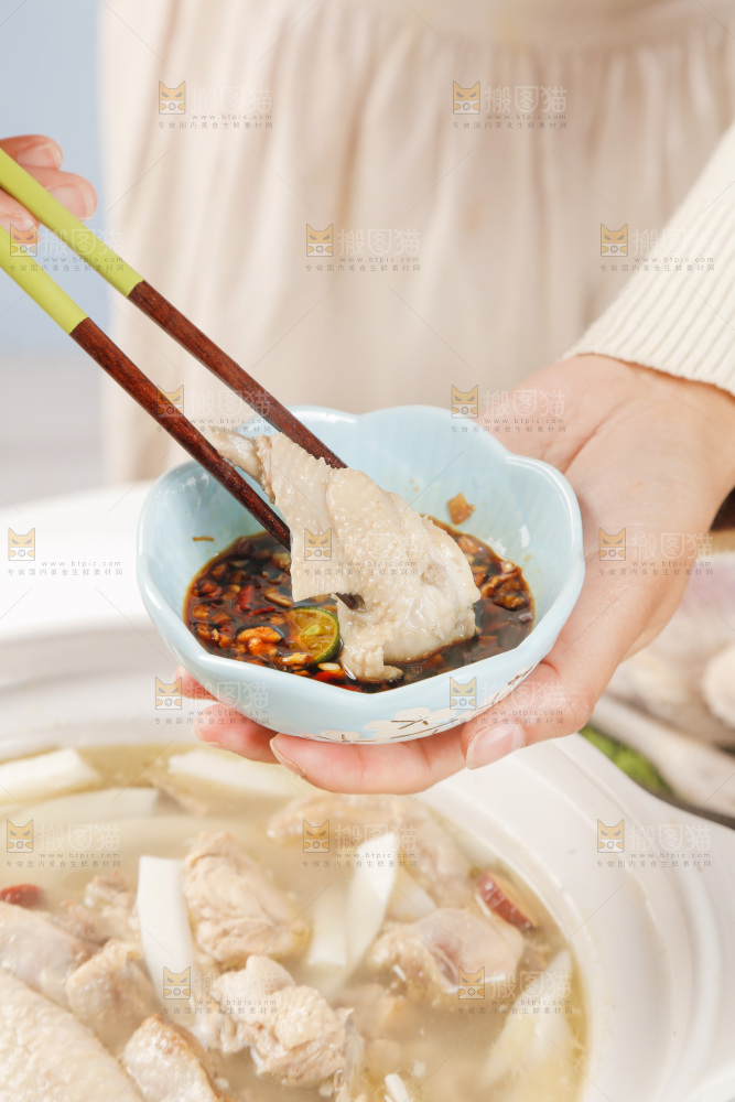 筷子上夹着蘸汁的椰子鸡