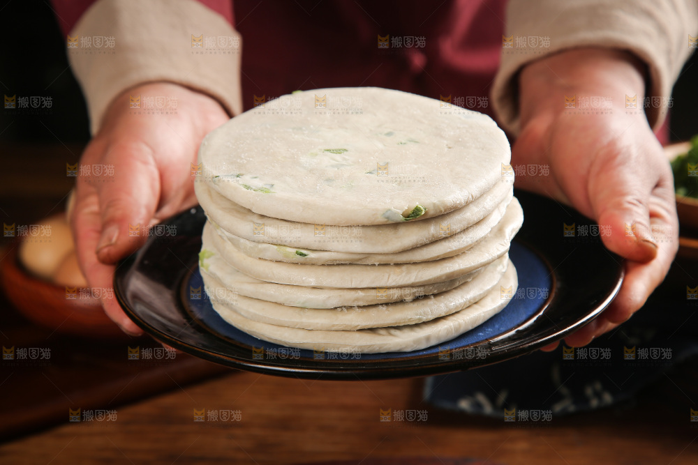 手里端着一盘葱油饼