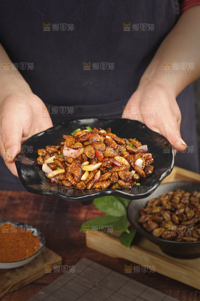 手里端着一盘香辣蚕蛹