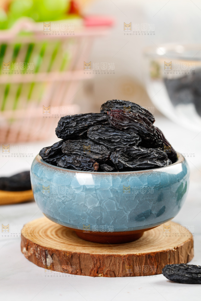 木板上放着一碗黑葡萄干