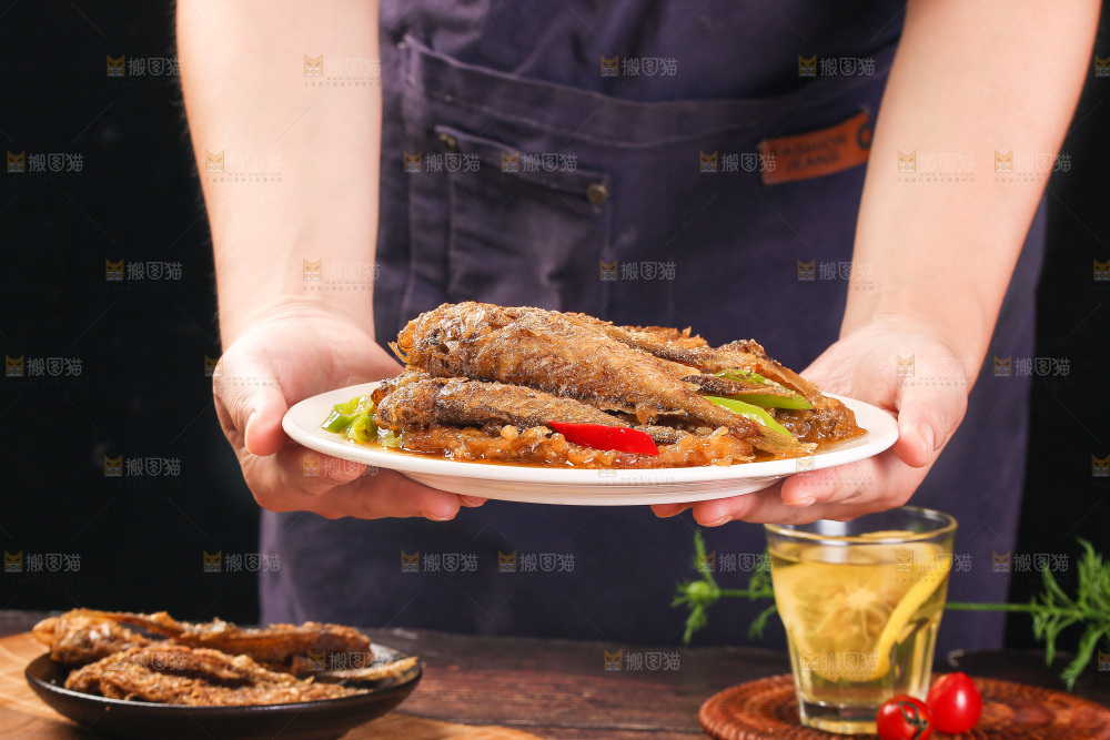 手端着一盘香酥煎鱼