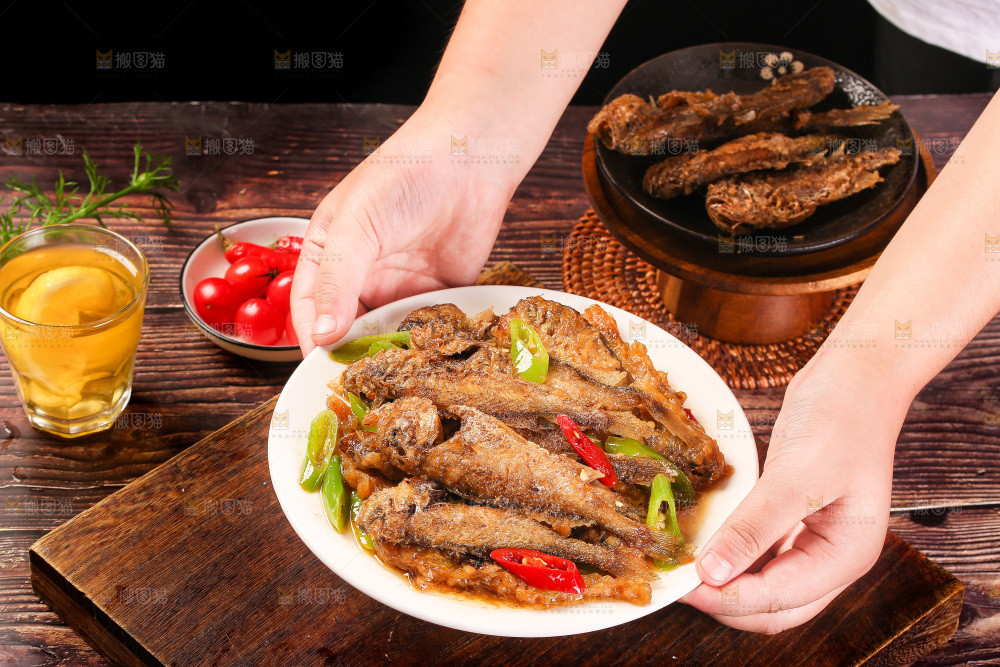 手端着一盘香酥煎鱼