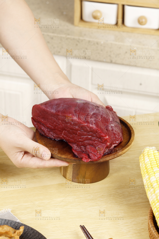 手端着一盘生牛肉