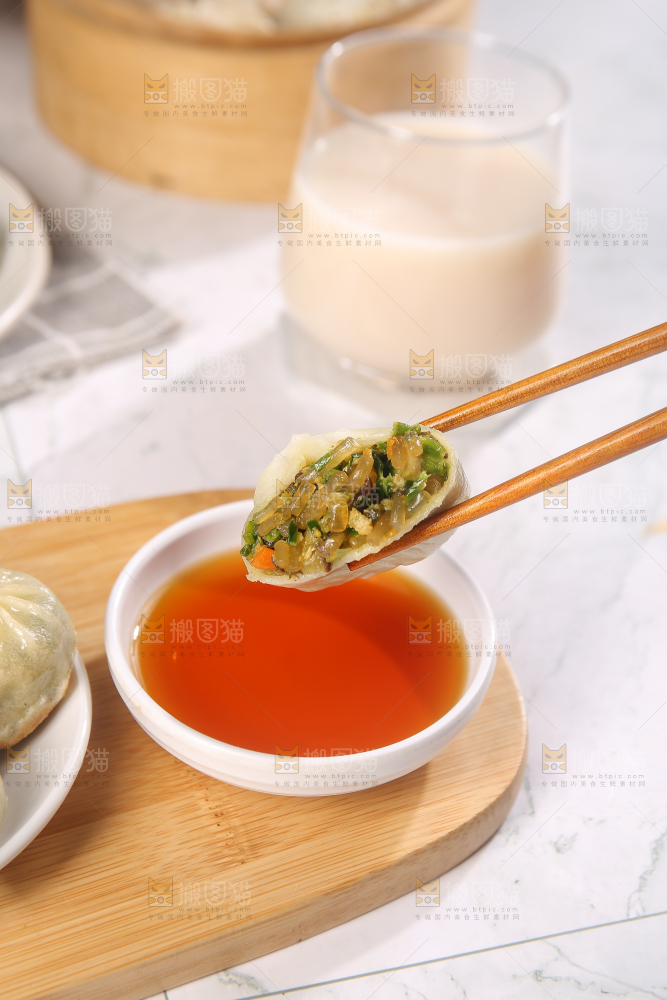 筷子夹着蘸料的小包子