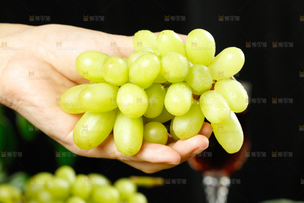 手里拿着一串新疆无核白葡萄