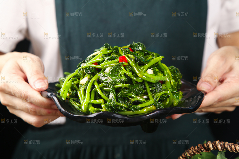 手里端着一盘炝炒苕尖