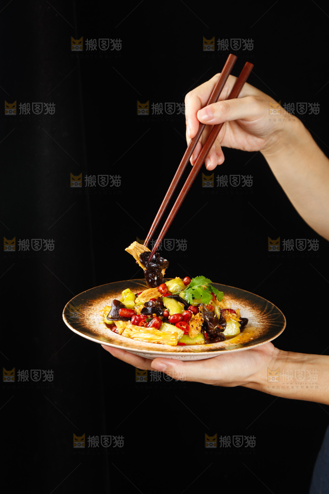 手里端着一盘凉拌腐竹黄瓜