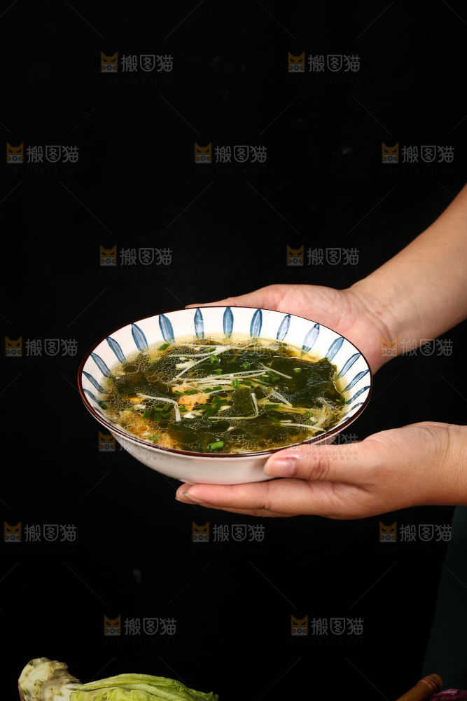 手里端着一盘裙带菜汤