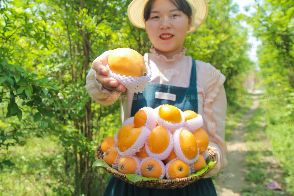 女人手里端着一篮大枇杷