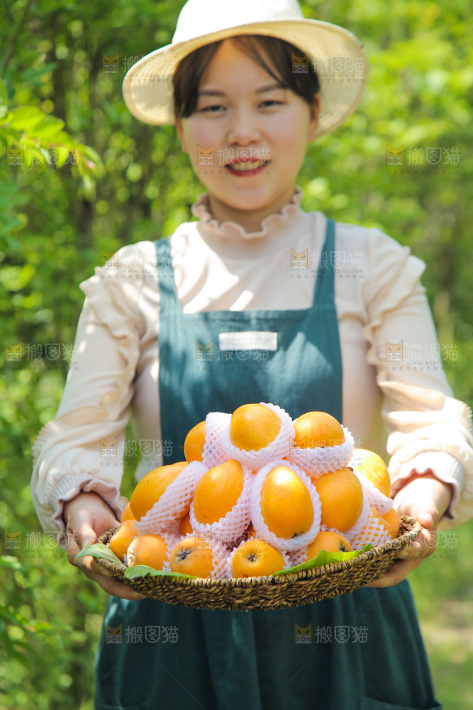 女人手里端着一篮大枇杷