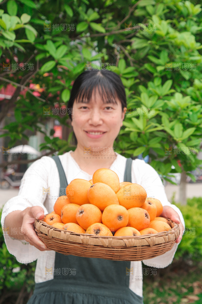 女人手里端着一篮枇杷