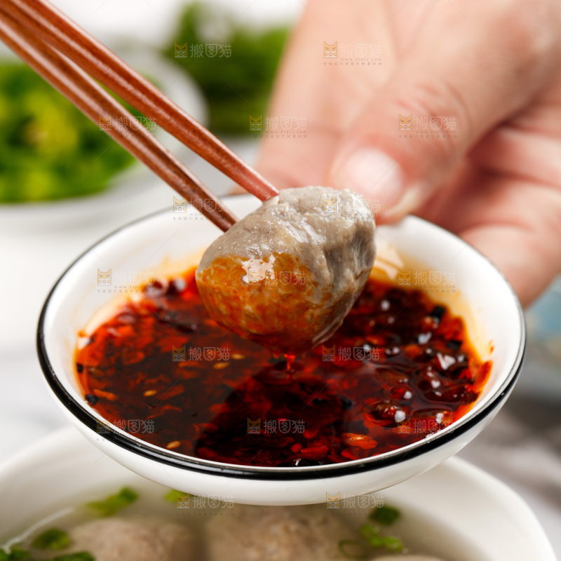 筷子夹着牛肉丸蘸辣椒