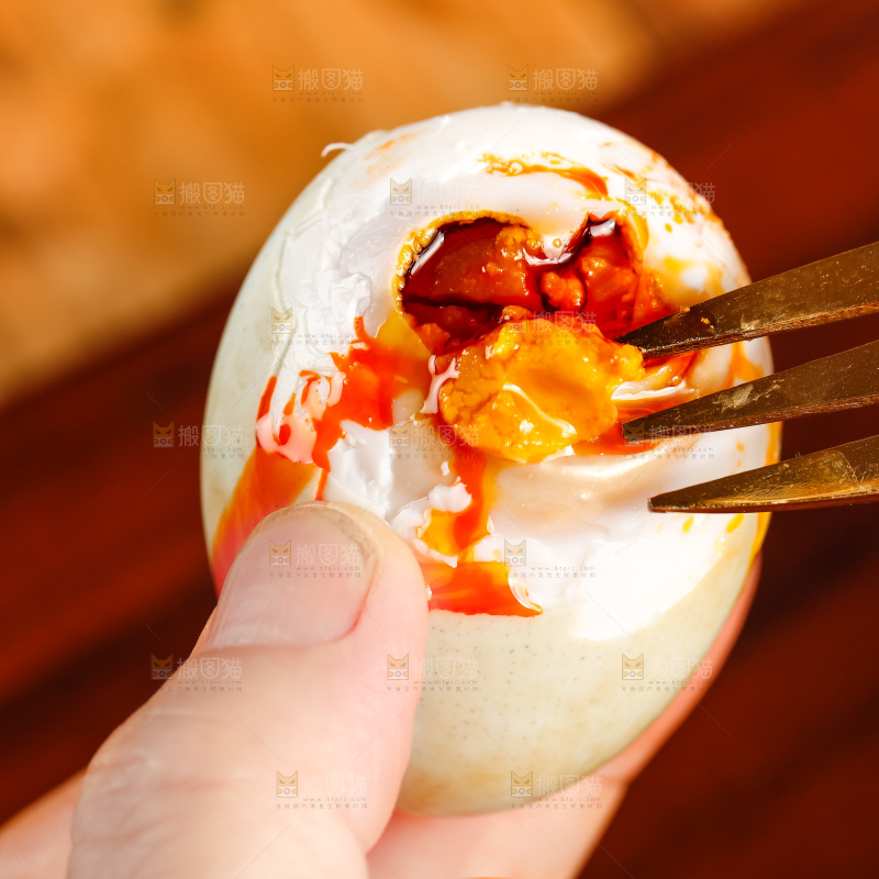 木板上手拿流油的海鸭蛋
