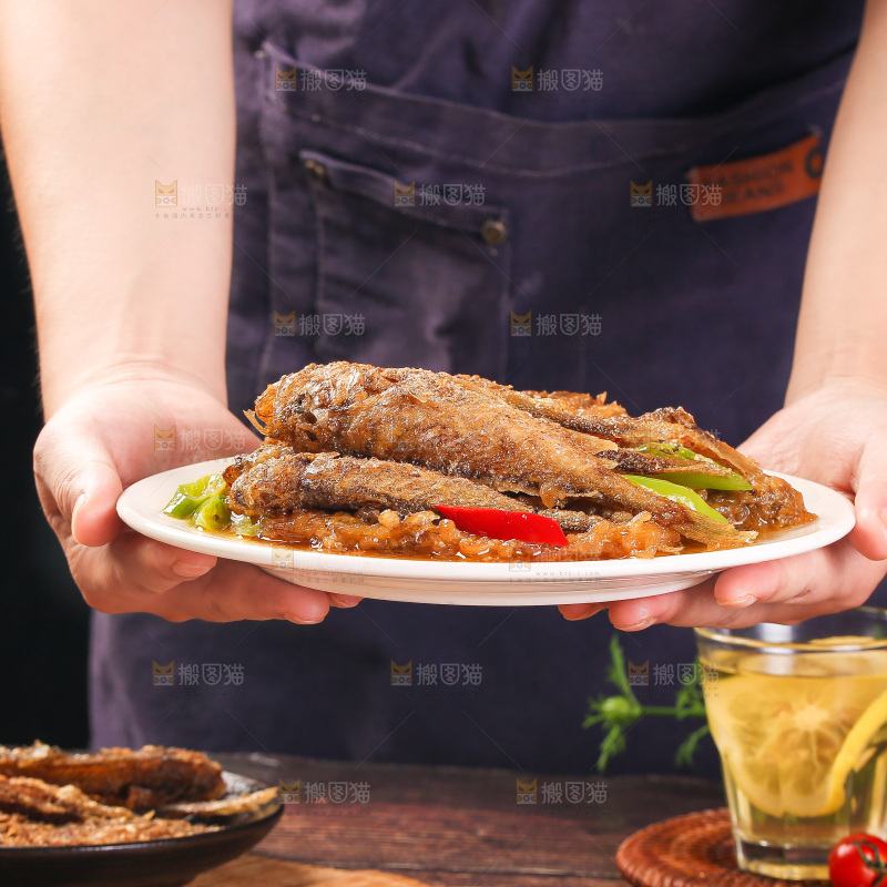 手端着一盘香酥煎鱼