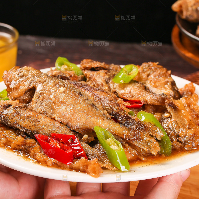 手端着一盘香酥煎鱼