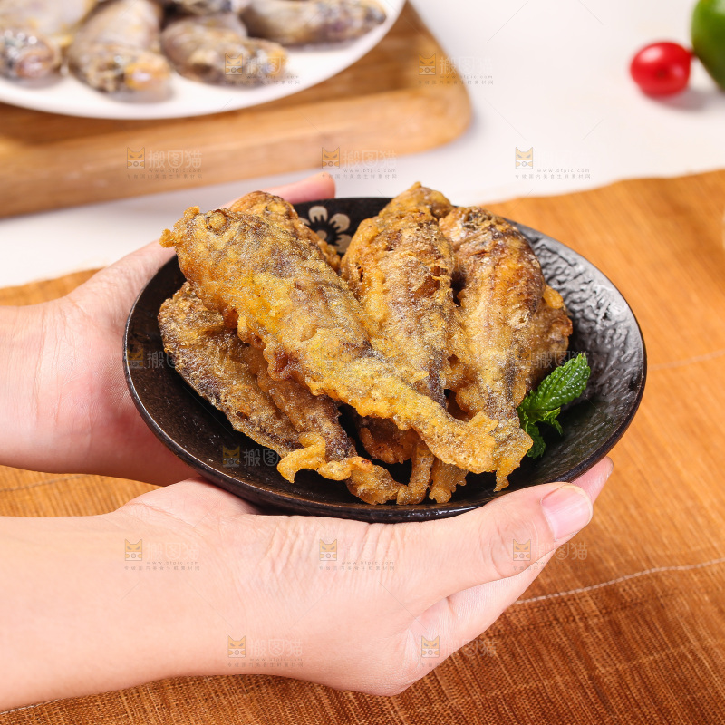 手端着一盘香炸小鱼