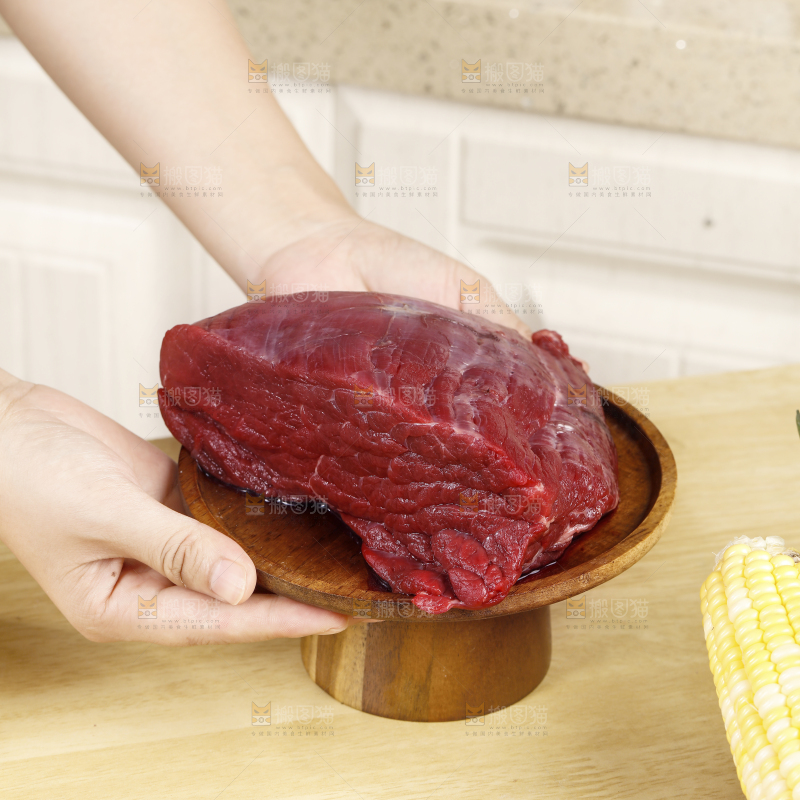 手端着一盘生牛肉