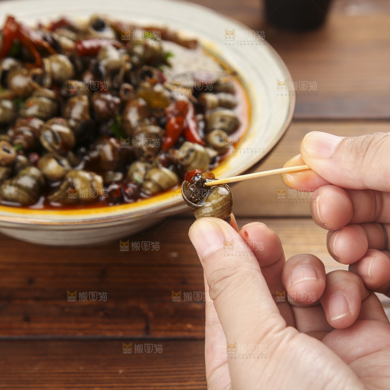 手里拿着牙签挑田螺肉