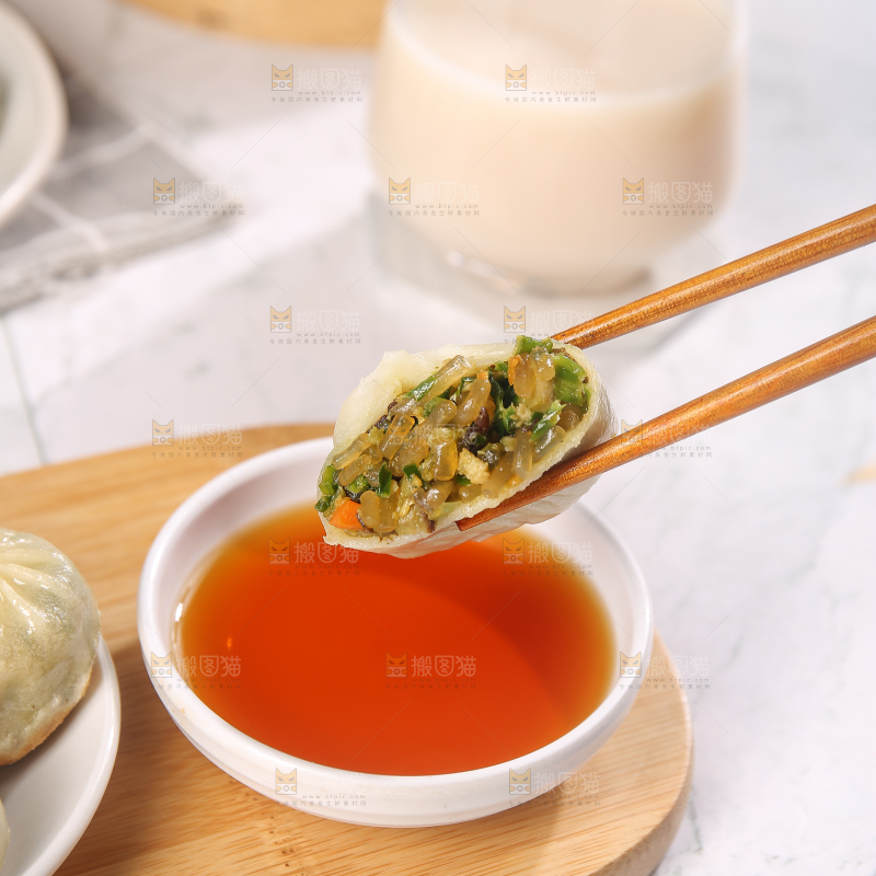 筷子夹着蘸料的小包子