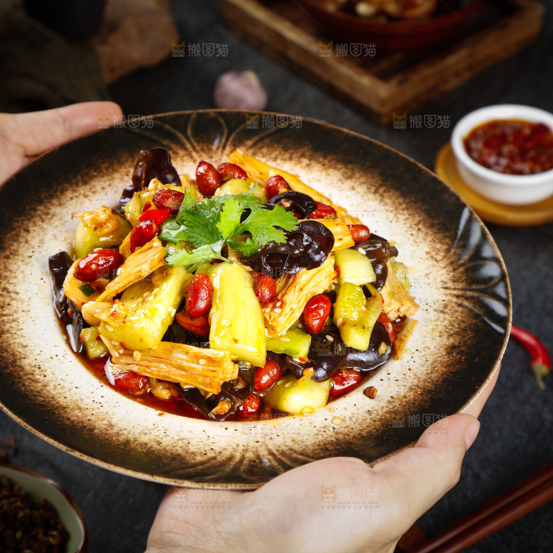 手里端着一盘凉拌腐竹黄瓜
