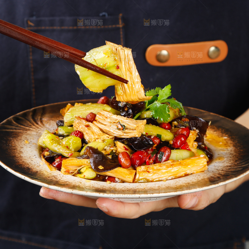 手里端着一盘凉拌腐竹黄瓜
