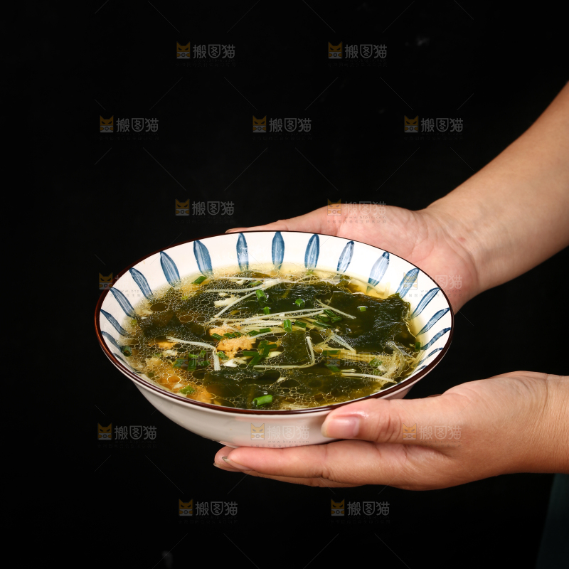手里端着一盘裙带菜汤
